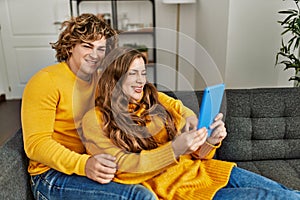 Young caucasian couple using touchpad hugging each other at home