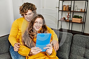 Young caucasian couple using touchpad hugging each other at home