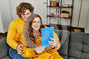 Young caucasian couple using touchpad hugging each other at home