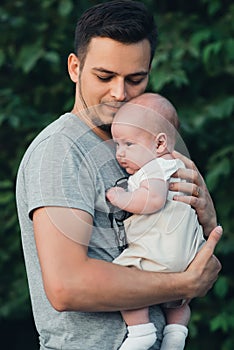 young Caucasian dad with beard hugs newborn baby boy son