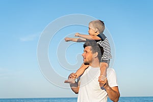 Young Caucasian dad with little son walk warm summer day along the sea coast. Summer family vacation concept. Friendship father