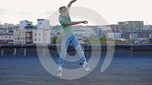 Young caucasian dancer performing contemporary outside on the roof. Man enjoying dance,looking at camera. Male performer