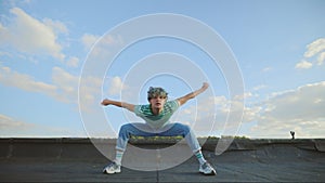 Young caucasian dancer performing contemporary outside on the rooftop. Man enjoying dance,looking at camera. Male