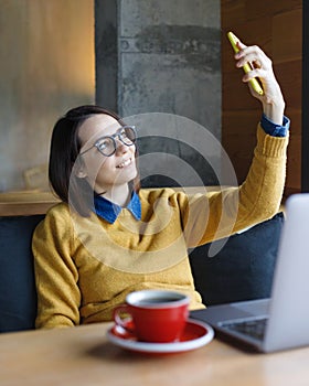 a young Caucasian, European woman in a blue denim shirt and glasses is working on a laptop