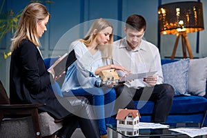 Young caucasian family with designer on the meeting in the modern blue office.