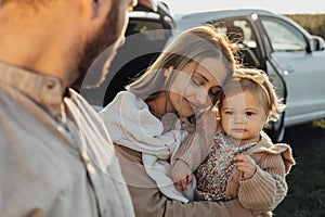Young Caucasian Family Enjoying Road Trip, Mother and Father with Little Daughter Outdoors with SUV Car on the
