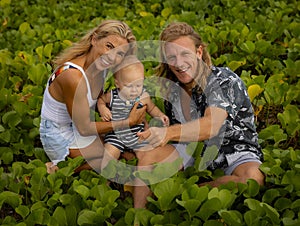 Young Caucasian family of father, mother and son spending time in nature. Outdoor activities. Mum, dad and baby boy sitting on the