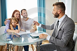 Young caucasian family getting keys from their house by real estate agent