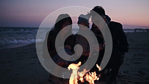 Young caucasian family sitting by campfire and enjoying the closeness outdoors when spending evening together on