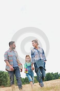 Young Caucasian family walking across field with young girl holding bouquet of flowers, concept organic ecologically friendly fami photo