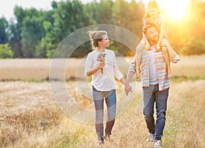 Young Caucasian family walking across field with young girl holding bouquet of flowers, concept organic ecologically friendly fami photo