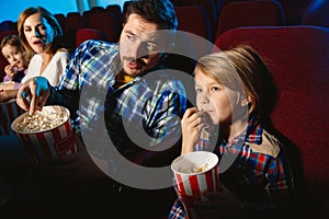 Young caucasian family watching a film at a movie theater