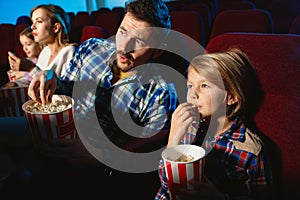 Young caucasian family watching a film at a movie theater