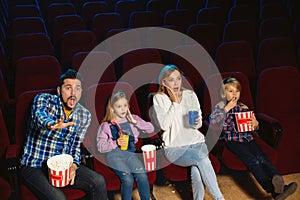 Young caucasian family watching a film at a movie theater