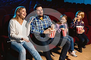 Young caucasian family watching a film at a movie theater