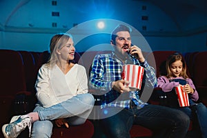 Young caucasian family watching a film at a movie theater