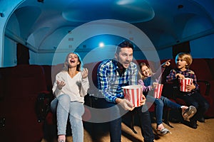 Young caucasian family watching a film at a movie theater