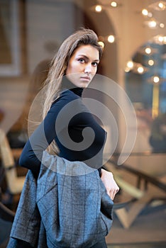 Young caucasian fashionable woman dressed in black clothesposing outdoor, Christmas Eve. Beautiful caucasian girl in Milan, Italy