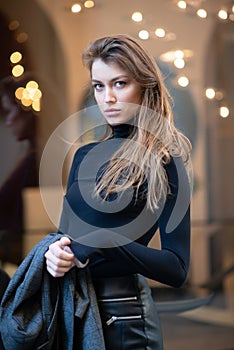 Young caucasian fashionable woman dressed in black clothesposing outdoor, Christmas Eve. Beautiful caucasian girl in Milan, Italy