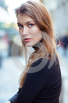 Young caucasian fashionable woman dressed in black clothesposing outdoor, Christmas Eve. Beautiful caucasian girl in Milan, Italy