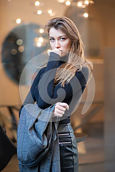 Young caucasian fashionable woman dressed in black clothesposing outdoor, Christmas Eve. Beautiful caucasian girl in Milan, Italy