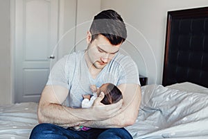 Young Caucasian father dad with his newborn mixed race Asian Chinese baby. Male man parent holding child daughter son.