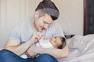 Young Caucasian father dad with his newborn mixed race Asian Chinese baby. Male man parent holding child daughter son.
