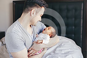 Caucasian father dad with newborn mixed race Asian Chinese yawning baby. Man parent holding child