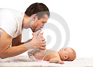 Young Caucasian father kissing feet of his baby son