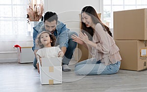 Young Caucasian father playing with little daughter that sitting inside cardboard box while unpacking move to new house