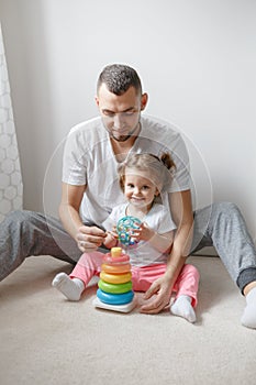 Young Caucasian father playing toys with child girl. Male man parent entertains toddler daughter sitting at home. photo