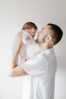 Young Caucasian father trying to calm down newborn baby. Male man parent holding rocking child daughter son on his hands.