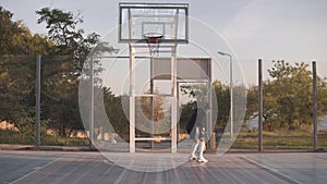 Young caucasian female basketball player exercising and practicing ball handling skill on court. Backside view