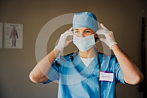 Young caucasian female doctor in scrubs with medical mask