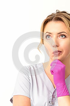 Young caucasian female doctor wearing gloves thoughtful looking away against a white background.