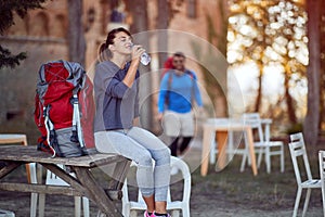 Young caucasian female drinking water, sitting, having a break from hiking