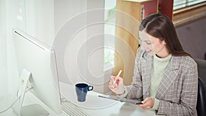 Young caucasian female entrepreneur sitting at desk in home office and checking financial data on digital tablet