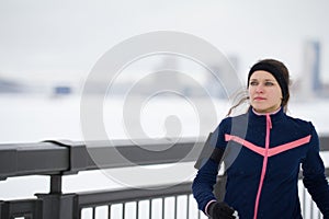 Young caucasian female fitness model running at snow winter promenade, close up