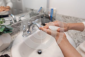 Young Caucasian Female Hands Lathering White Bar Hand Soap for Washing and Personal Hygiene, and Then Rinsing Hand Under Sink Wate