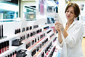 Young caucasian female makes lipstick samples on her hand