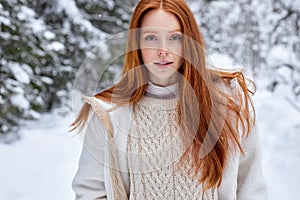 young caucasian female model with red hair posing at camera in winter forest, alone