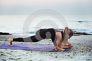 Young caucasian female practicing yoga on the seaside