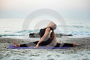 Young caucasian female practicing yoga on the seaside