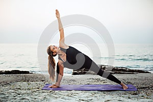 Young caucasian female practicing yoga on the seaside