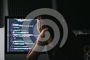 Young caucasian female programmer in glasses writes program code on a computer