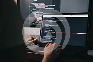 Young caucasian female programmer in glasses writes program code on a laptop