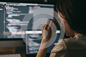 Young caucasian female programmer in glasses writes program code on a laptop