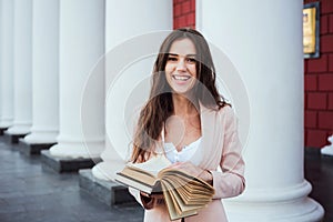 Young caucasian female student with books on campus