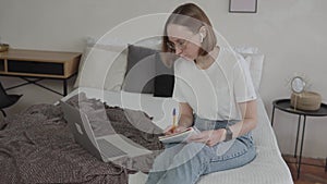 Young caucasian female student looking at laptop studying from home.