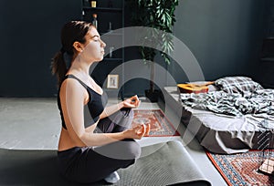 Young caucasian fitness woman meditate, doing yoga indoors at home near the bed. Staying fit and healthy